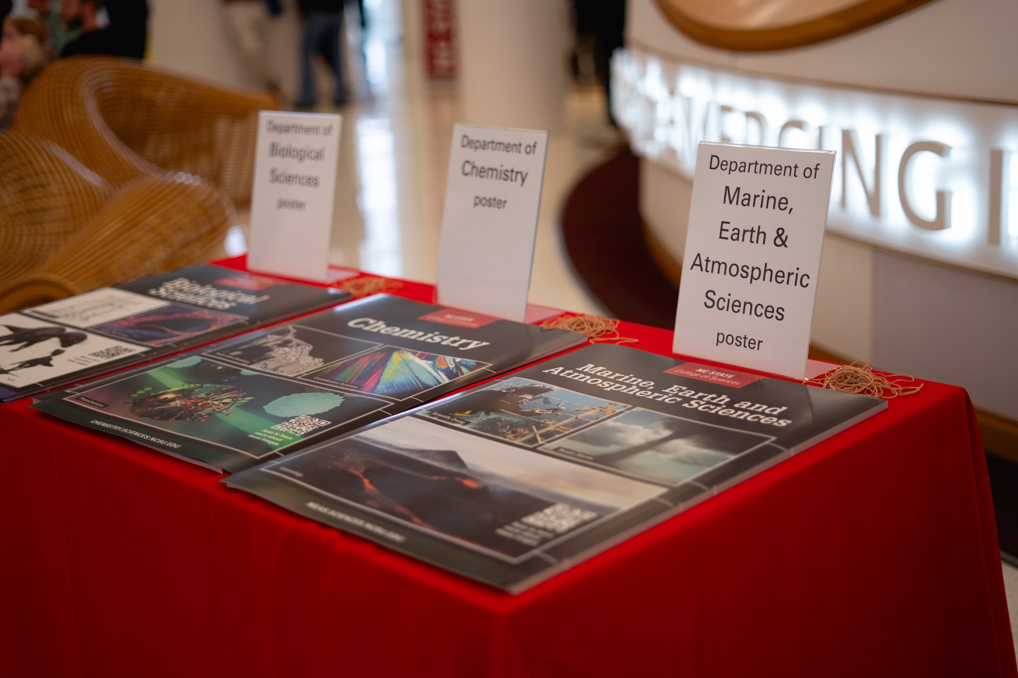 Posters for each department, including MEAS, on a table at the entrance to the State of the Sciences