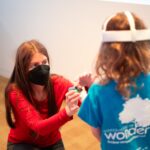 Arianna Soldati assists a child with the controls for a VR headset