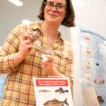 Lily Hughes holds a preserved fish specimen in a jar