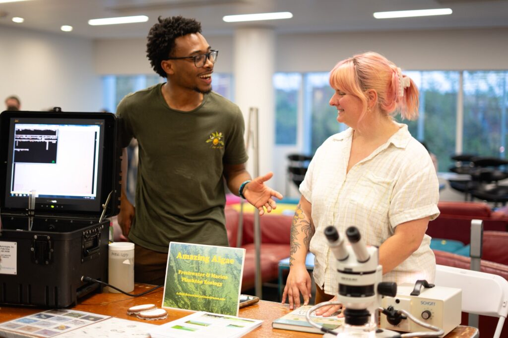 Chayse Jones and Lucy Roussa talk at their booth