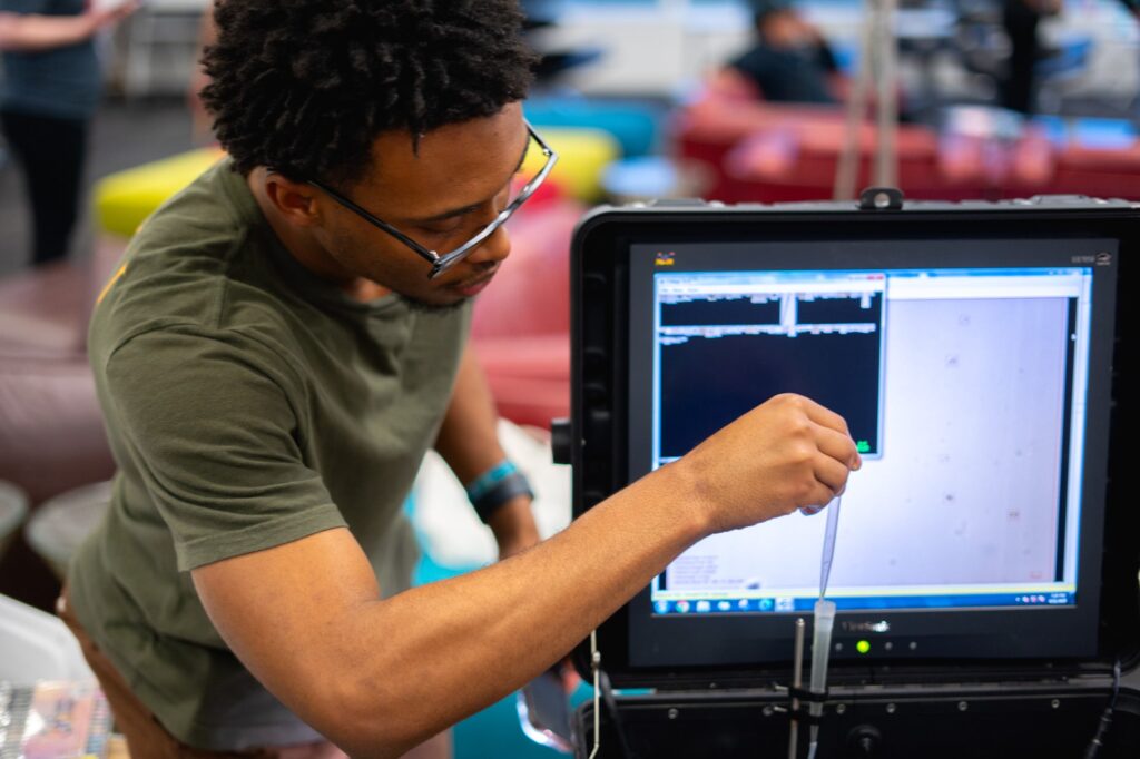 Chayse Jones uses a dropper-like tool to add more algae to a device used to identify them.
