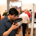 Camilo Rey-Sanchez blows into a domed device that helps measure blow speed and greenhouse gas emissions
