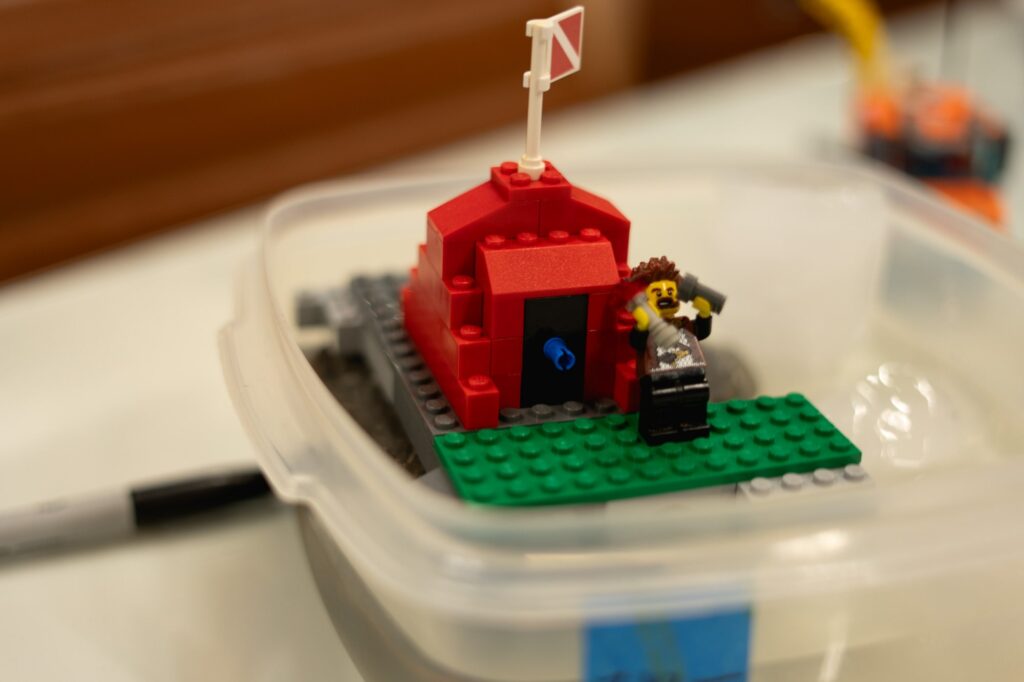 A lego pirate floats in a container with melting ice.