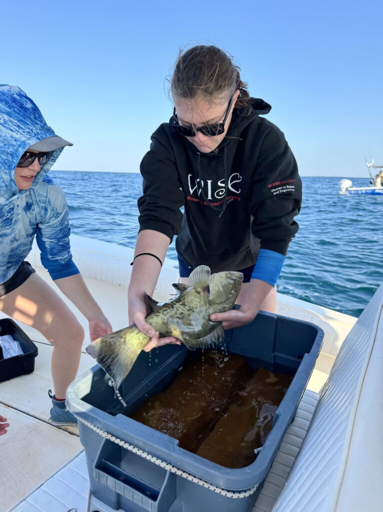 Fleming holds a gag grouper fish on a boat
