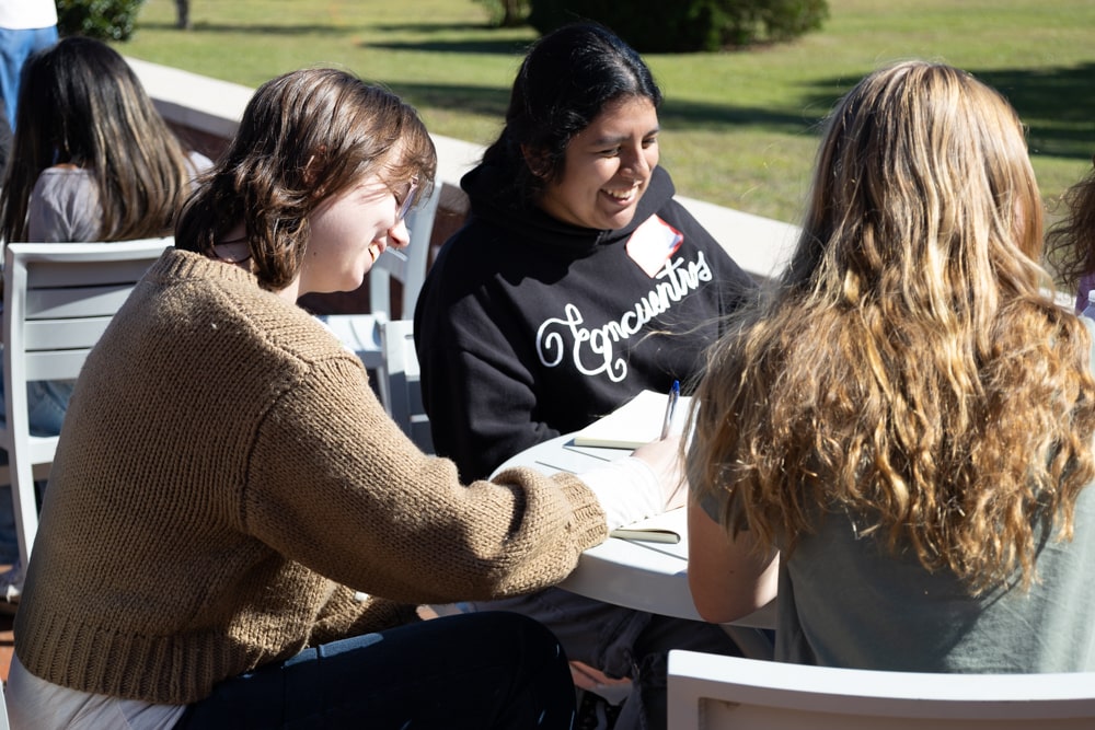Students smile while working on their project pitches