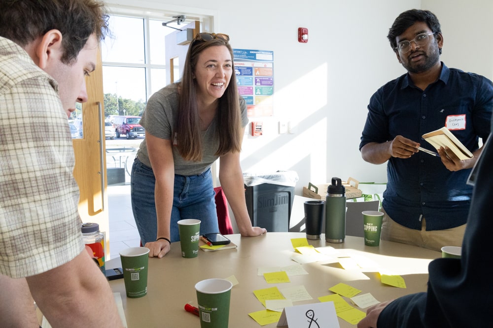 Attendees at the blue foods table brainstorm with a sticky-note covered table